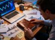 Retail CFD trader at a desk reviewing a trading journal, with charts and scattered notes suggesting the danger of reading false patterns into small samples.
